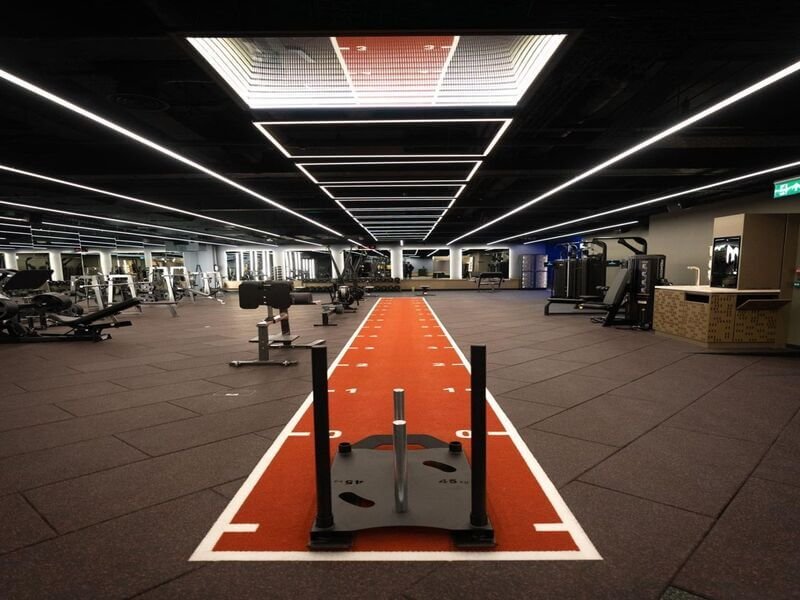 Athletes performing sled pushes on indoor turf for gym