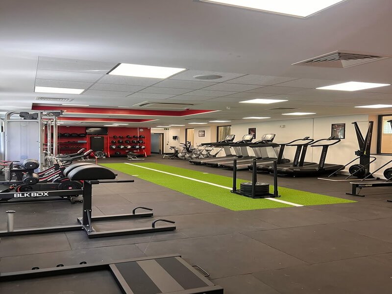 Athlete doing sled push on green Shock Turf