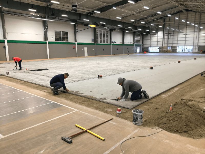 Ein sauberer und ebener Betonboden wird für die Verlegung von Turnrasen vorbereitet