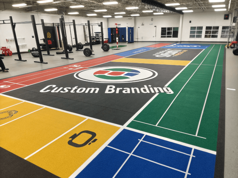 A gym floor with custom branding, including a large logo and colored zones.