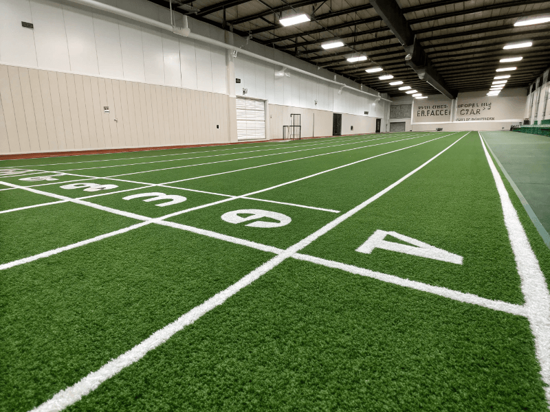 Eine unberührte, leere Turnhallenrasenbahn mit klaren weißen Markierungen