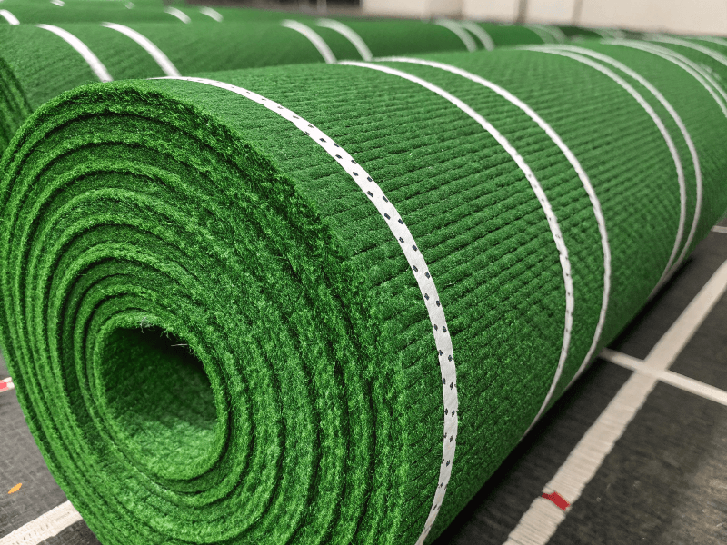 A roll of green gym turf with white woven-in hash marks ready for installation.